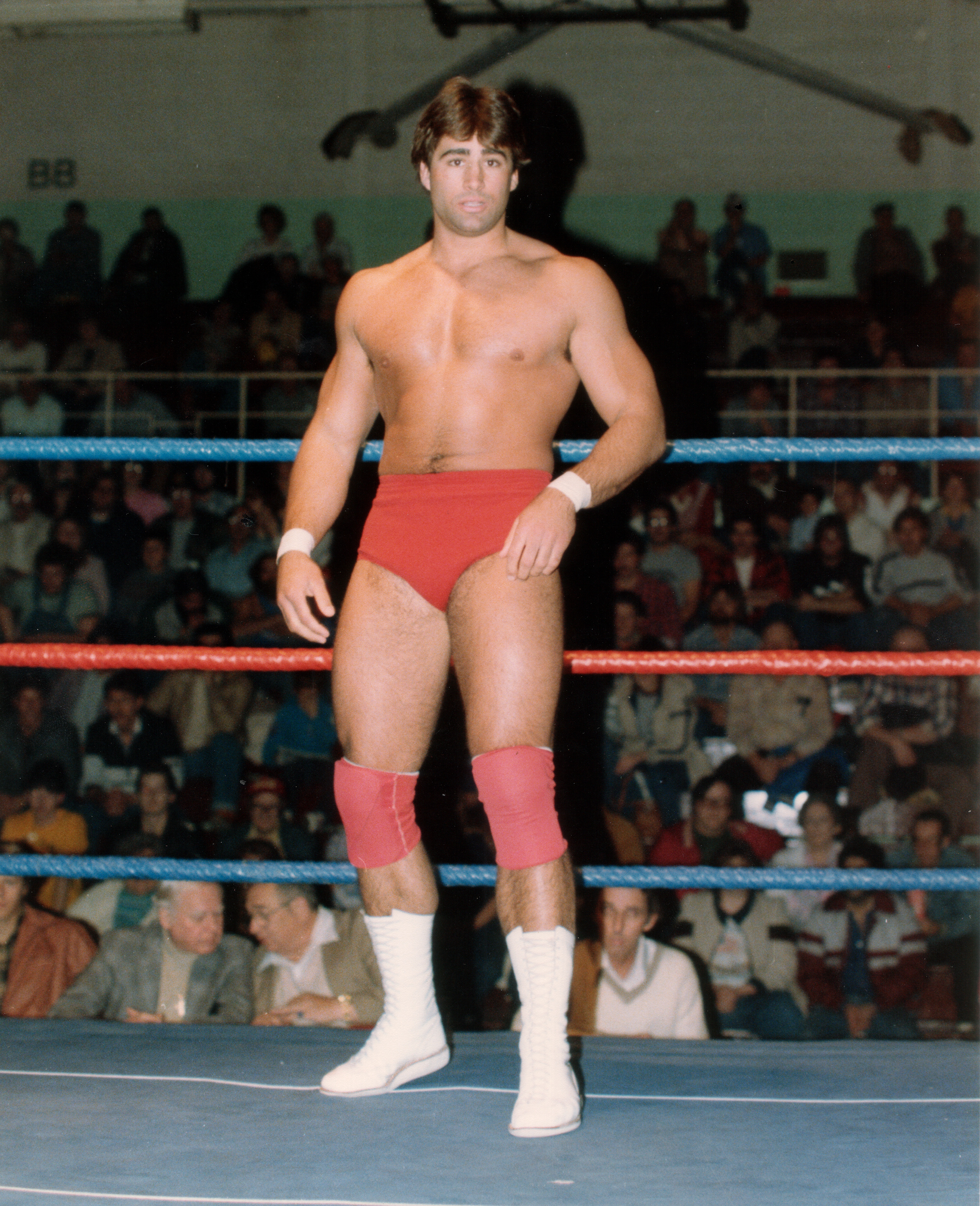 Tom Zenk standing in an AWA ring in red trunks